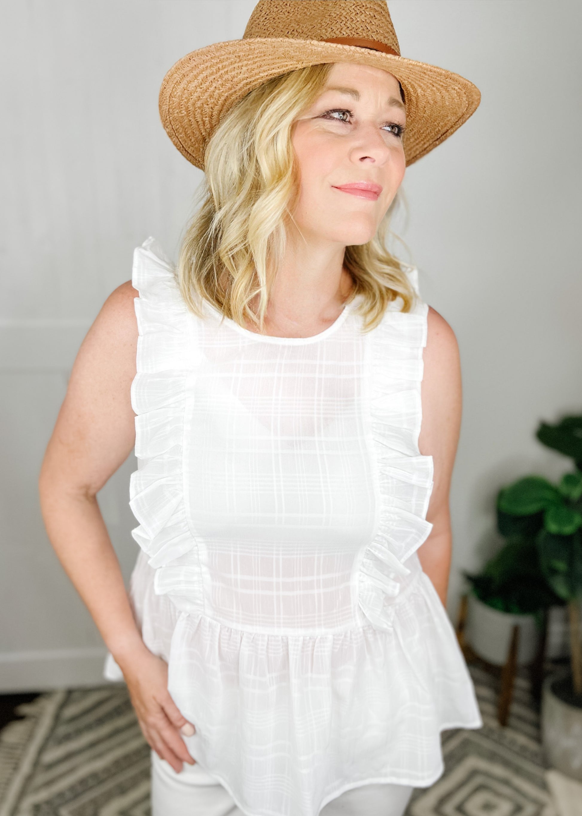 White sleeveless peplum with inset plaid pattern. Vertical ruffles from shoulder to waist. 