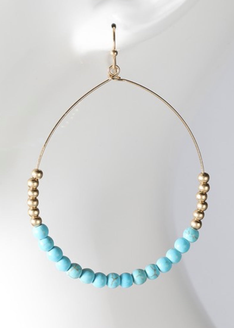 Turquoise hoop earrings with a natural stone and metal bead. 