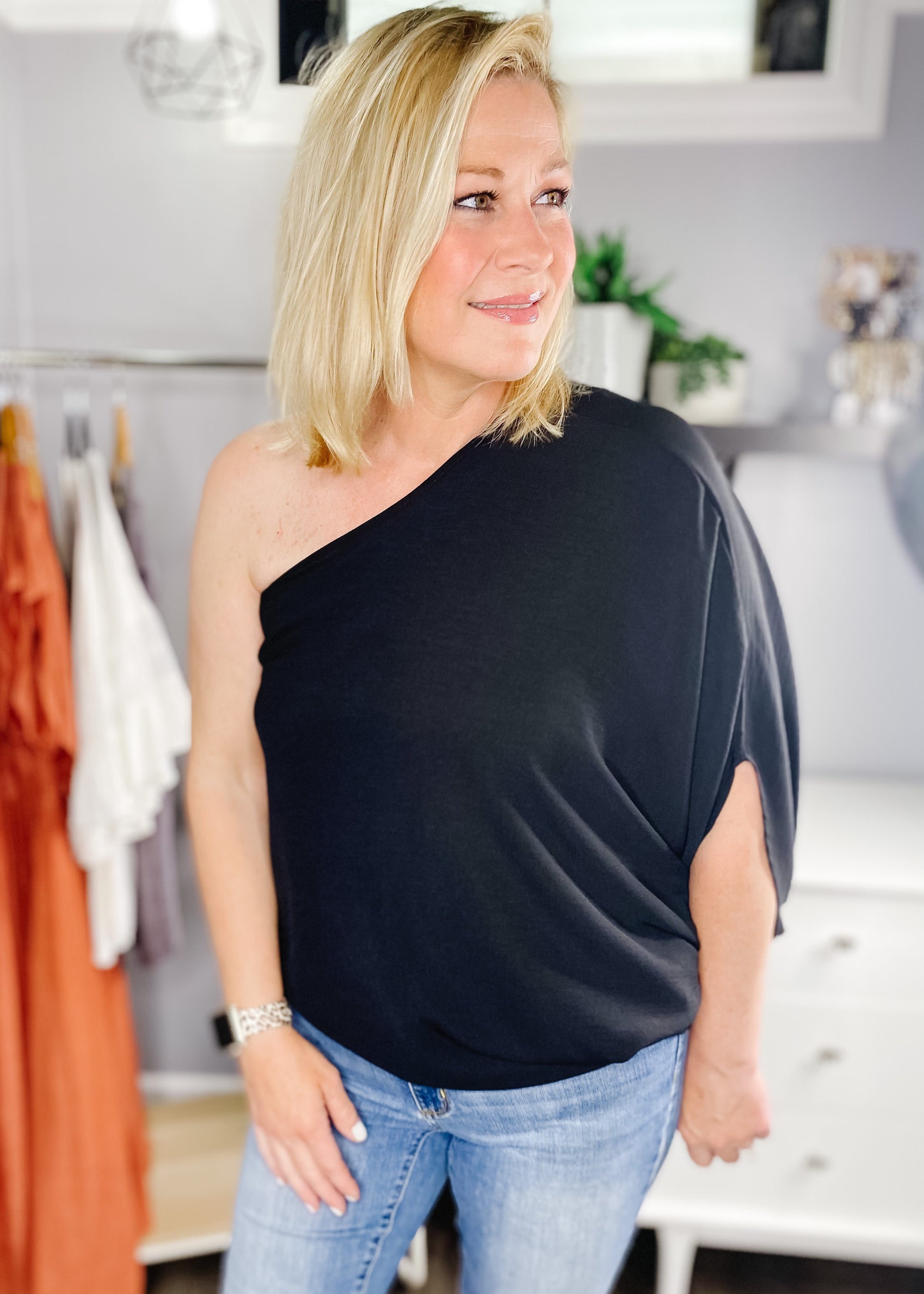 Stunning one shoulder top in black. Top features a one should with dolman sleeve to elbow, light flowy fabric in all black.  Available in small, medium and large.